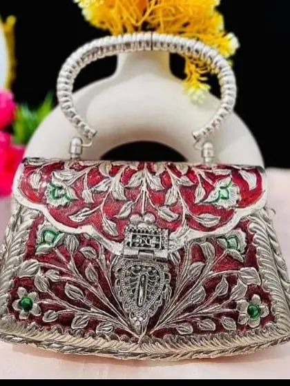 I love adding a touch of color to classic designs. This silver clutch features beautiful red and green enamel work, known as meenakari, making it a vibrant and unique statement piece.