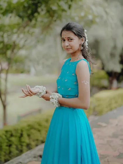 A graceful pose showing the model in her vibrant blue lehenga, with floral wristbands adding to the 'Krishna-sakhi' theme.
