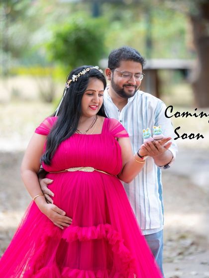 A sweet couple photo with a "Coming Soon" message, featuring tiny baby shoes as a prop.
