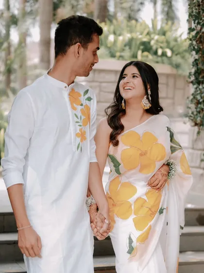 Divya and Chaitanya look lovingly at each other, their matching floral outfits perfectly complementing the garden setting. This is a great example of a bright and happy pre-wedding portrait.