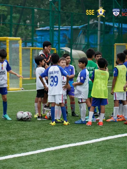 A coach leading a team talk on the pitch. These moments are crucial for building strategy and team cohesion.