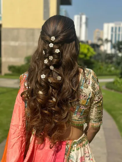 For this wedding guest look, I created a half-up style with soft curls and scattered small floral pins throughout the hair for a dispersed, delicate effect.