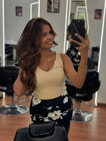 A client taking a mirror selfie to capture her fabulous new hair, featuring fresh color and a bouncy, salon-perfect style.