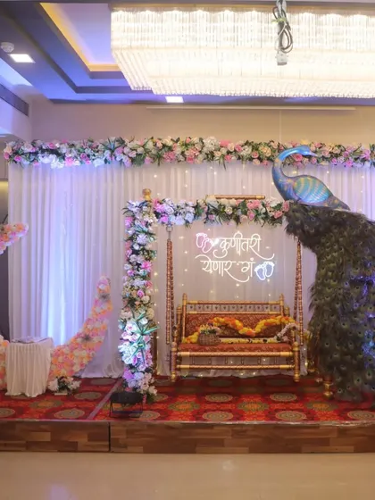 This is one of my favorite Dohale Jevan setups. It combines all the popular elements: a traditional jhula, a beautiful peacock prop, a custom neon sign, and a floral moon seat for photos.