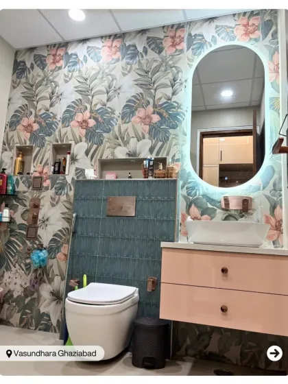 This bathroom is a tropical paradise, featuring a vibrant floral and leaf-patterned wallpaper. The pink vanity and teal half-wall tiles add to the playful and refreshing vibe.