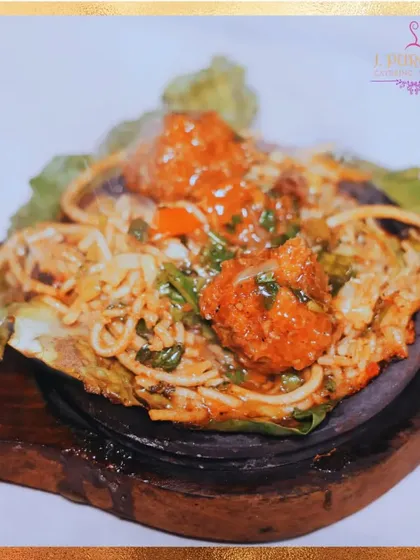 A close-up of a freshly prepared vegetable manchurian sizzler, served steaming hot. The sizzle and aroma from the live station always draw a crowd.