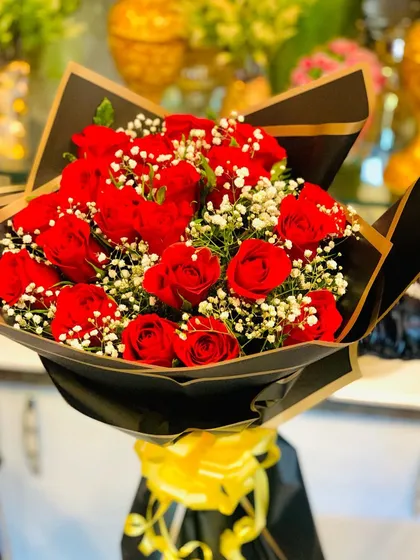 A classic bouquet of red roses and baby's breath in a sophisticated black wrap with gold edging. The yellow ribbon adds a pop of color to this timeless arrangement.