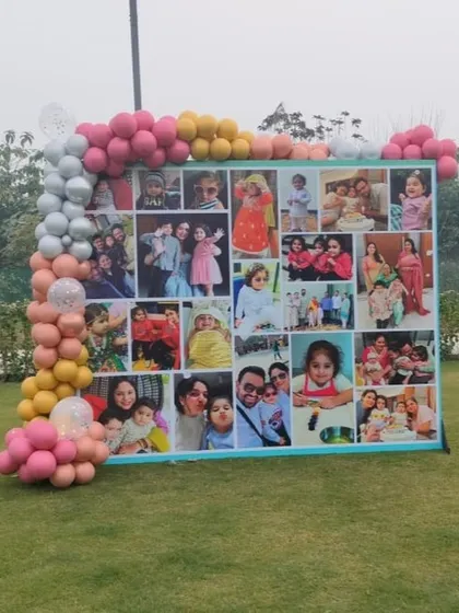 A wide shot of the photo collage backdrop, showing how it can be a central feature for an outdoor party. The balloon garland adds a festive frame to the display.