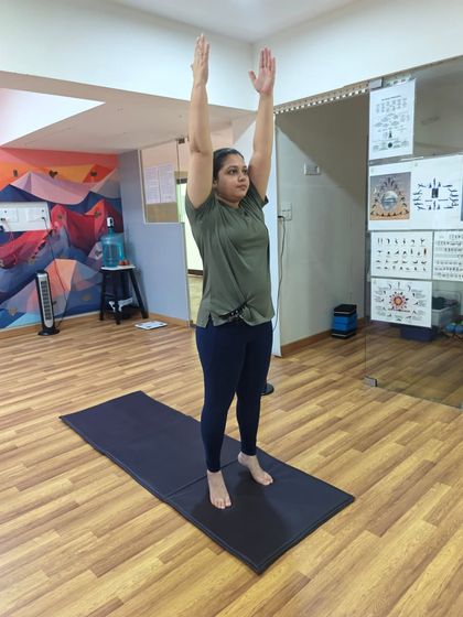 A student practices Tadasana, reaching for the sky. This posture improves posture, firms the abdomen and buttocks, and creates a sense of expansion.