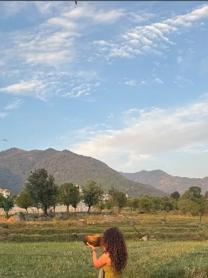 I believe that healing is deeply connected to nature. This moment, captured during one of our retreats, shows me with a Tibetan singing bowl against the backdrop of the mountains, a practice of gratitude and surrender. It represents my philosophy of taking our healing practices out of the studio and into the world to connect with the earth's energy.