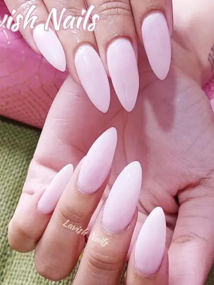 A simple yet striking set of long, stiletto-shaped nails in a soft, milky pink color.