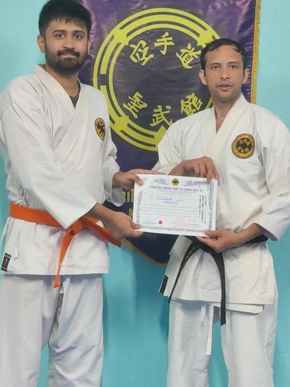 Presenting an adult student with his 7th Kyu (orange belt). His progress shows that consistent effort leads to tangible results in martial arts.