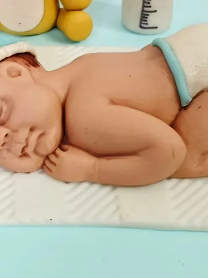 A close-up of the incredibly detailed, handcrafted sleeping baby figurine from the welcome cake. It's these little touches that make a cake truly special.