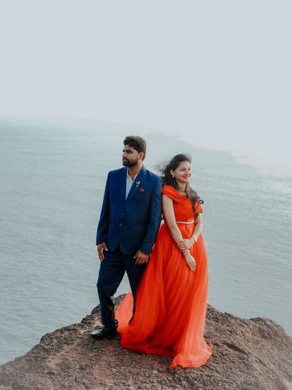 A beautiful pre-wedding portrait on a cliff. The bright red gown stands out against the misty ocean backdrop, creating a powerful and romantic image.