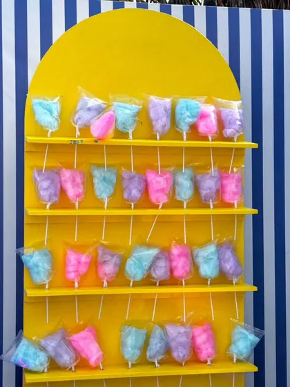 The colorful cotton candy display stands against a blue and white striped backdrop, offering a sweet and photogenic moment for guests at the Uttarayan celebration.