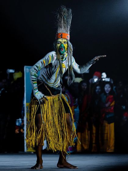 A tribal performer in full costume and face paint, poised in a dynamic stance on stage. This photo showcases the energy and unique visual storytelling of cultural dances in India.