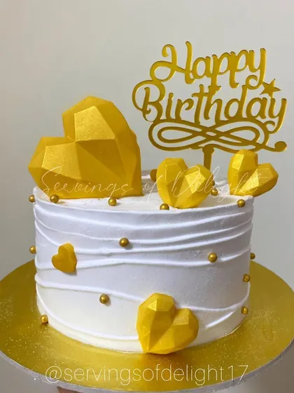 A classic white and gold birthday cake decorated with geometric chocolate hearts. This half-kg cake is perfect for smaller, yet equally special, celebrations.