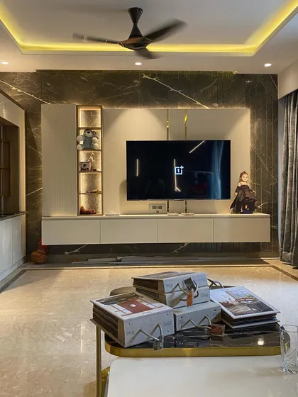 An integrated TV wall unit designed for a modern living room. The unit is set against a full-height marble slab and includes custom shelving and concealed storage.