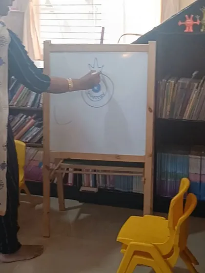 The storyteller adds details to the monster drawing, showing the children how to add personality to their creations.
