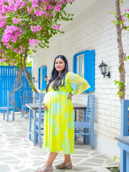 A beautiful solo portrait of the mother-to-be in a bright yellow dress, enjoying a moment in a charming outdoor cafe.