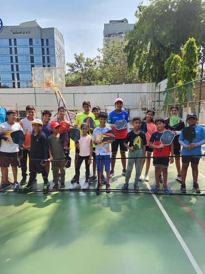 Our pickleball program is perfect for learning a new sport that combines fun, fitness, and competition. Here, a group of players and coaches pose on the court at our Matunga facility.