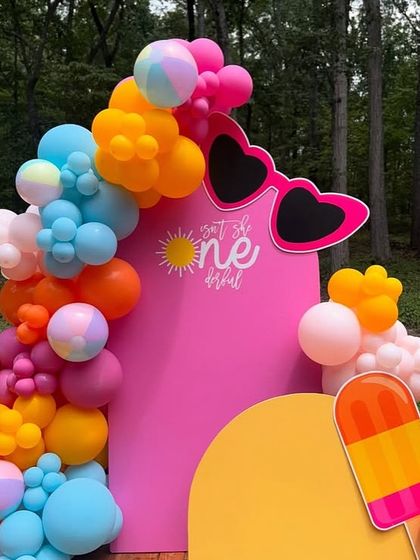 Another angle of the vibrant summer-themed party, showing the 'Isn't she ONEderful' text on the pink backdrop.
