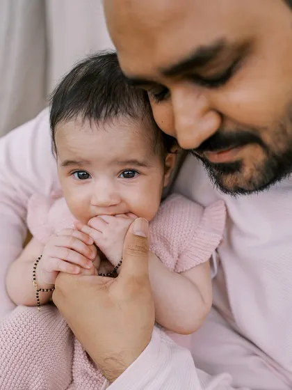 A father holding his three-month-old daughter. You can see the love and connection in his gentle embrace.