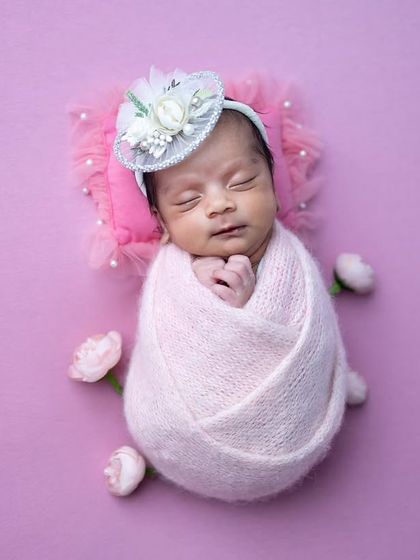 A simple and elegant 'potato sack' pose on a pink background, surrounded by delicate flower buds.