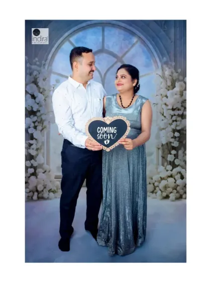 The happy couple holds a "Coming Soon" sign, a classic and adorable announcement pose from their studio maternity photoshoot.