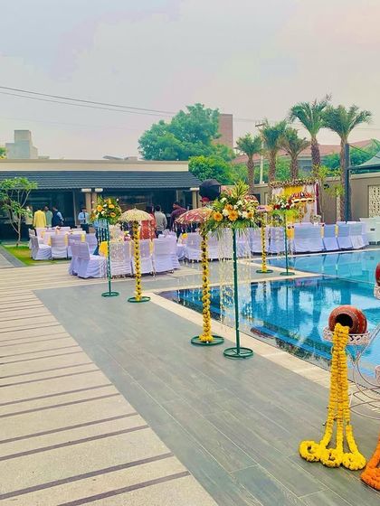 A poolside view of a Haldi event setup. The decor includes marigold arrangements and traditional hanging pots that complement the outdoor venue perfectly.