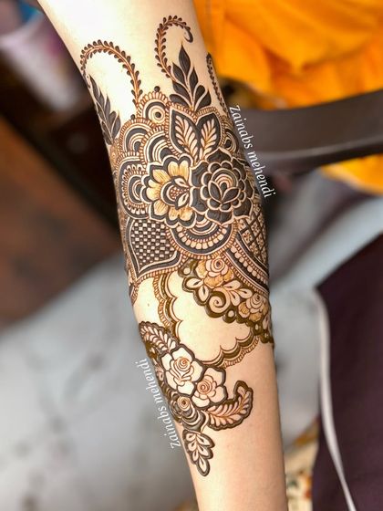 A close-up of the forearm portion of Arfa's bridal henna, showcasing the intricate floral and paisley work.