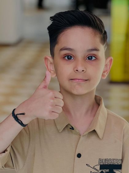 Even our youngest clients get the VIP treatment. This young man is giving a thumbs-up to his cool and stylish new haircut.