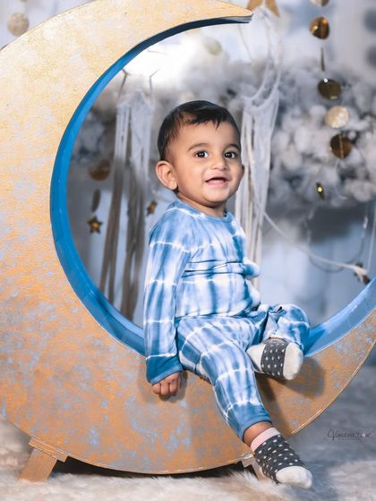 A happy toddler enjoying the celestial moon set. The soft, cloud-like floor is perfect for babies who are sitting or crawling, ensuring they are comfortable throughout the shoot.