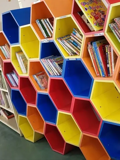 Our library is designed to be a vibrant and welcoming space where curiosity can thrive. This colorful honeycomb bookshelf is a favorite spot for kids to explore and find their next adventure. We believe a child's reading environment should be as imaginative and exciting as the stories themselves.