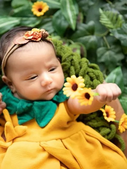 This one-month-old looks like a little sunflower herself. I used a cozy knit basket and a backdrop of lush leaves to create this nature-inspired newborn portrait, highlighting her delicate features.