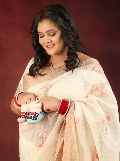 This close-up shot captures the mom-to-be smiling down at a pair of baby booties, a touching expression of her love for her unborn child.