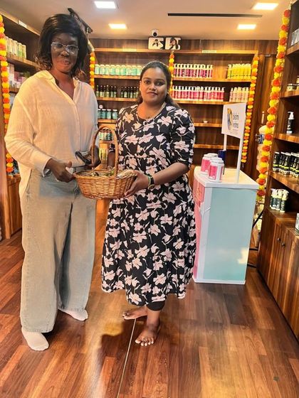 A happy international customer poses with our founder in our store, holding a basket full of Lakshmi Krishna Naturals products. We love sharing the purity of Ayurveda with everyone who walks through our doors.