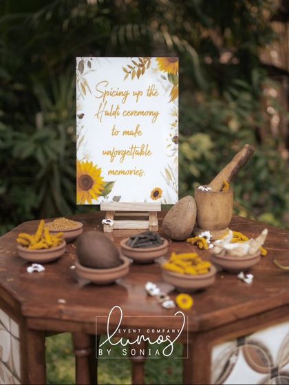 A beautiful setup for a Haldi ceremony, with bowls of turmeric and a sign that reads "Spicing up the Haldi ceremony."
