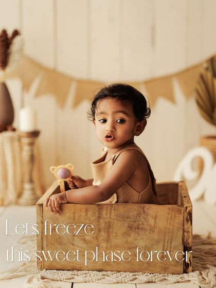Let's freeze this sweet phase forever. This baby is peeking out of a wooden box, a playful pose that captures their inquisitive nature.