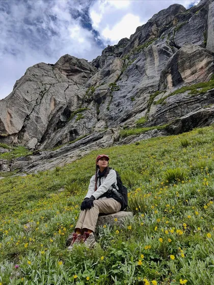 Taking a moment to soak it all in. The meadows on the Hampta Pass trek are filled with yellow wildflowers, set against dramatic rock faces.