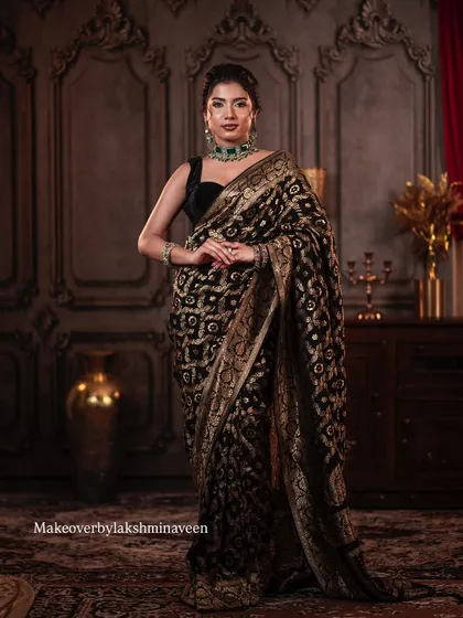A full-length shot showcasing the beautiful drape of the black and gold saree and the overall elegant posture.