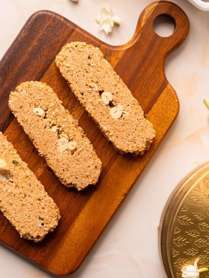 My Gajak bars on a wooden board, ready to be served. This simple, elegant presentation highlights the natural, rustic appeal of this beloved winter snack.