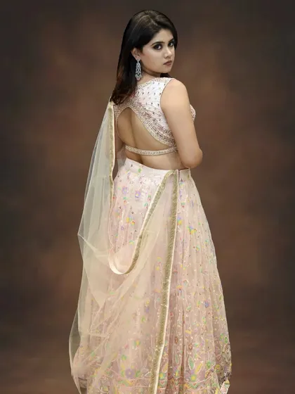 The stunning open-back design of this blush pink lehenga adds a touch of modern glamour. It's a detail that ensures you look beautiful from every angle as you walk down the aisle.
