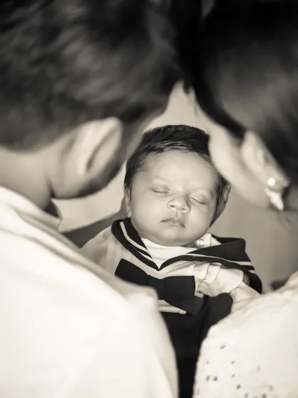 A touching black and white photo showing parents looking down lovingly at their newborn baby.
