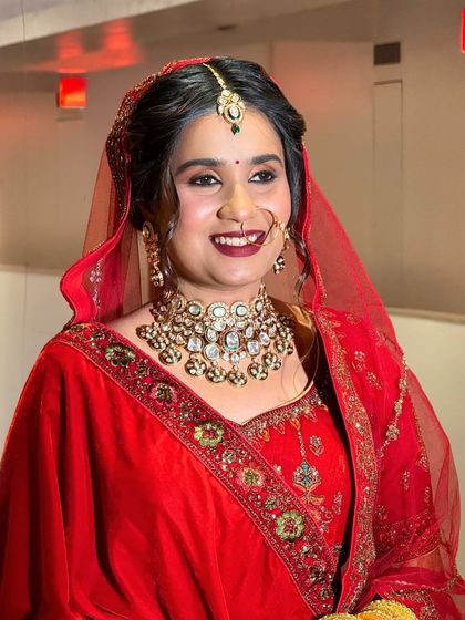 Another shot of a smiling bride in a red velvet lehenga, showing her joy and confidence. My goal is to make you feel amazing.