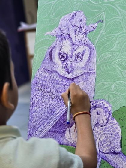 This action shot captures the moment of creation, as a young student adds details to his imaginative animal artwork using a ballpoint pen.