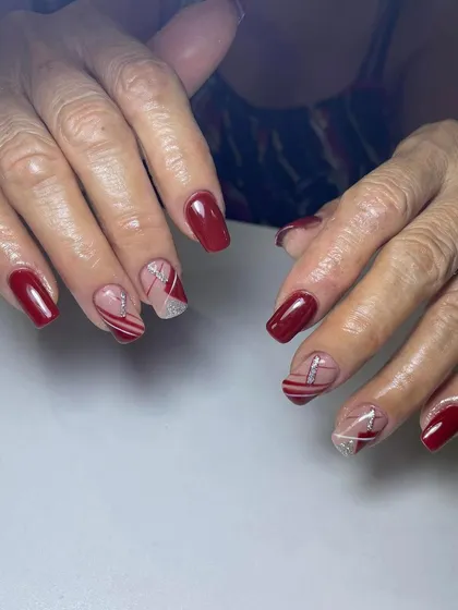 A classic red manicure with abstract line art and glitter on the accent nails. This is a great way to add a modern touch to a traditional color.