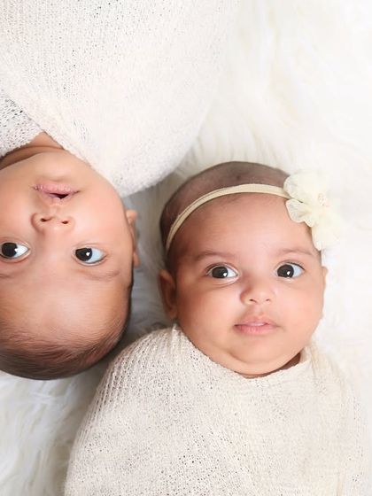 A simple and sweet portrait of two wide-eyed twins. Posed on a soft white blanket, their connection and individual personalities shine through.