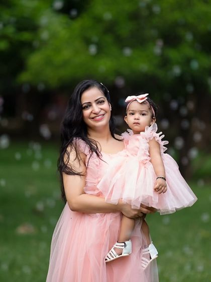 A mother and daughter in matching pink dresses, surrounded by bubbles in a park. This image captures a magical and playful moment.
