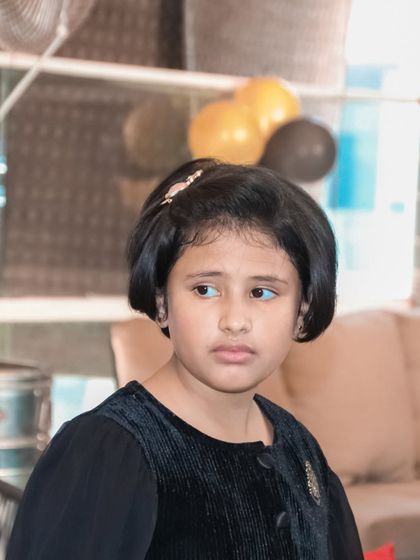 A candid portrait of a young girl with a thoughtful expression, taken during a family event.